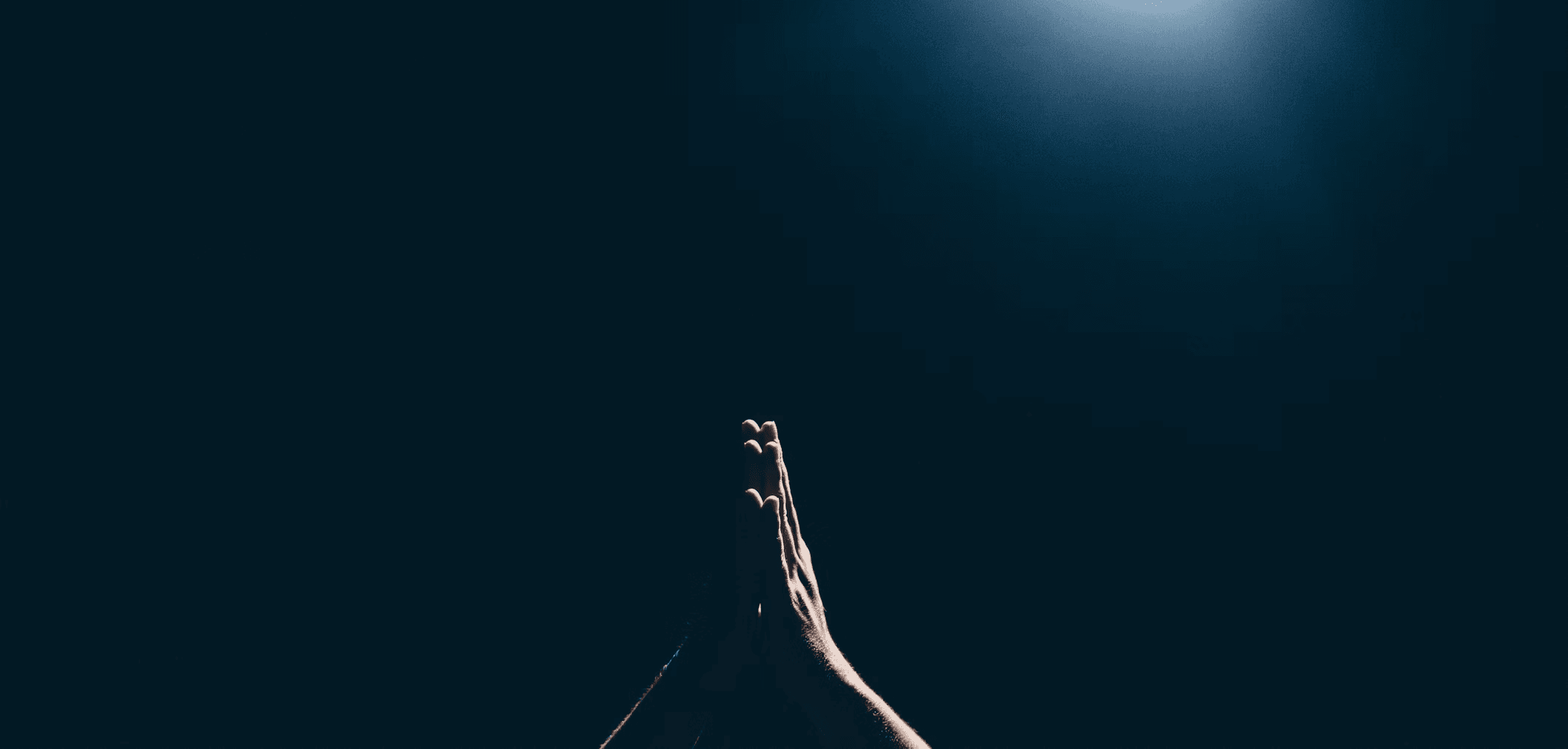 Mãos unidas em oração sob uma luz suave